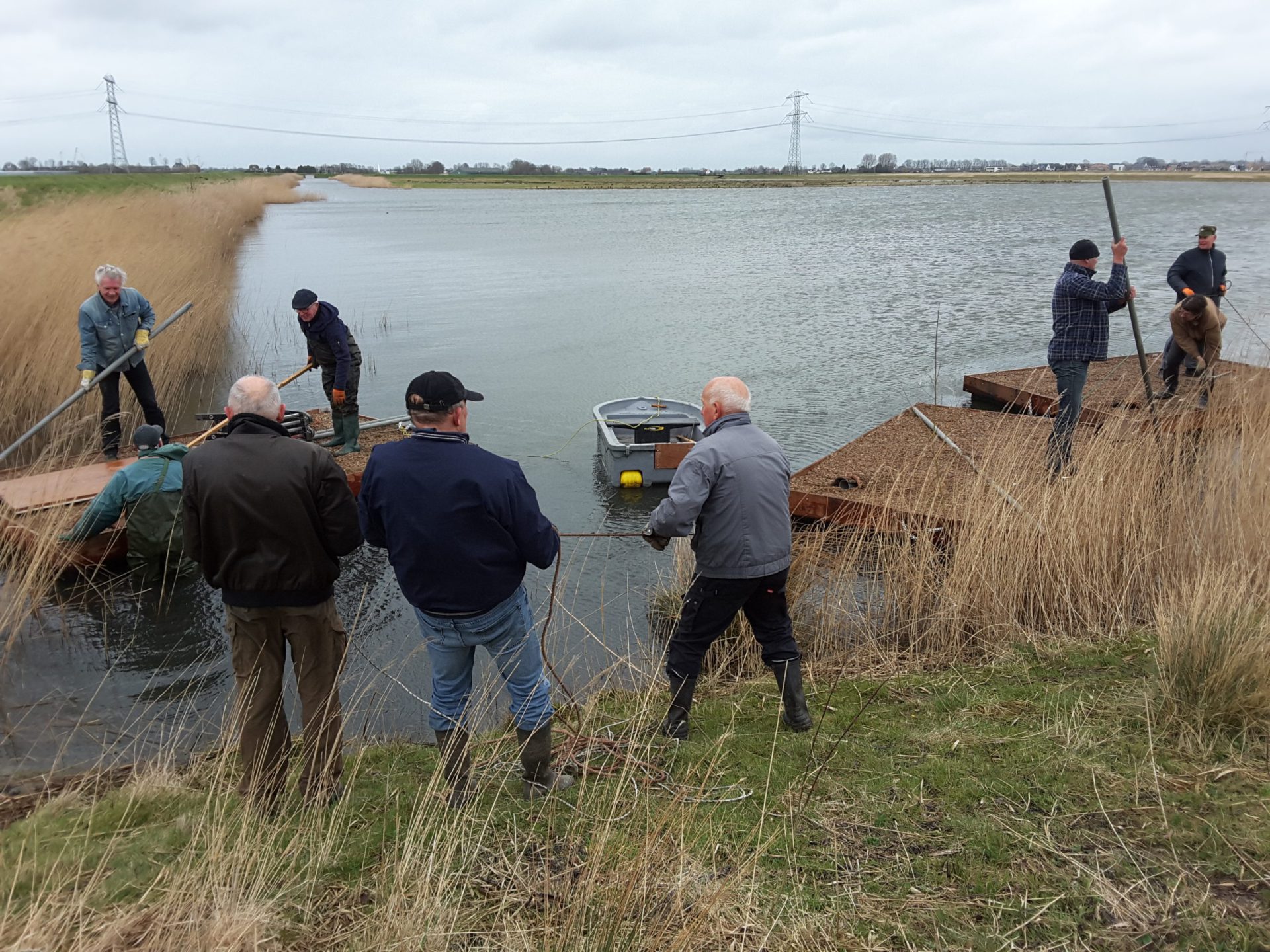 5. De eilandjes worden naar de hoek van de plas getrokken om vandaar, met de wind mee, naar de juiste plaats te varen.